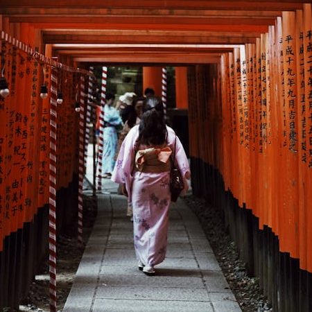 A woman in a kimono walks through the famous Torii gates of Fushimi Inari Shrine in Kyoto, Japan.
